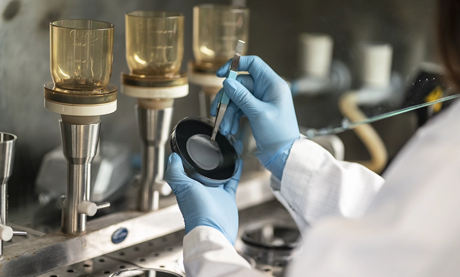 mani di un chimico che tiene delle pinze durante delle analisi nel laboratorio di Rivoli